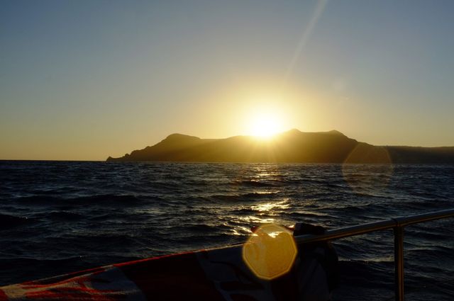 Sun setting behind mountain from boat